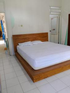a bedroom with a bed with a wooden bed frame at Kluwih House in Godean
