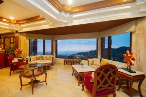 a living room with couches and tables and large windows at Amritara Surya - A Luxury Spa Retreat in Dharamshala