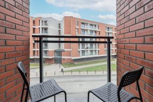格但斯克的住宿－Studio Fahrenheit in Central Gdańsk by Renters，一个带两把椅子的阳台和一座砖砌建筑