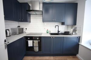 eine Küche mit blauen Schränken und einem Waschbecken in der Unterkunft Oxford's Most Stylish House - Garden & Parking in Oxford