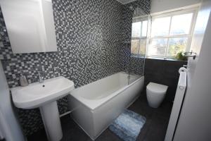 a bathroom with a sink and a tub and a toilet at Oxford's Most Stylish House - Garden & Parking in Oxford