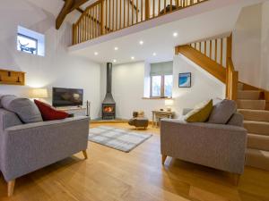 a living room with two couches and a staircase at Hoppers Barn in Holsworthy