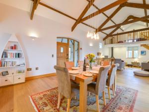 a dining room and living room with a wooden table and chairs at Hoppers Barn in Holsworthy