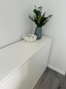 a white cabinet with a vase with flowers on it at Shellharbour Haven in Shellharbour
