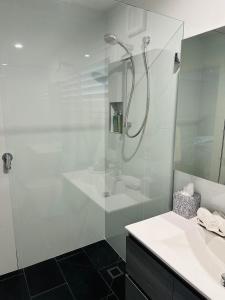 a white bathroom with a shower and a sink at Shellharbour Haven in Shellharbour