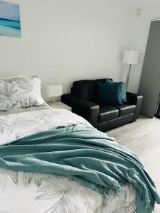 1 dormitorio con 1 cama y 1 sofá negro en Shellharbour Haven, en Shellharbour