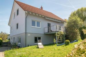 a white house with a balcony and a lawn at Ferienwohnung "Urlaub bei Lina" in Hergatz