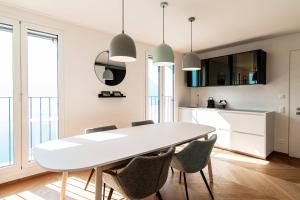 uma sala de jantar branca com uma mesa e cadeiras brancas em Unique Gandria 3 by Quokka 360 - luxury two-bedroom apartment with a breathtaking view em Lugano