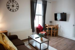 a living room with a couch and a table and a clock at Trinity, Central Cambridge Flat in Cambridge