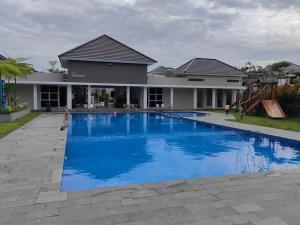 a large blue swimming pool in front of a house at Sweet City Villa near Mall Pekanbaru Sudirman in Pekanbaru