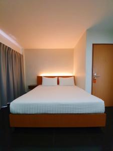 una camera da letto con un grande letto con lenzuola bianche di The Sila Suites - Intrawarorot a Chiang Mai