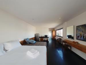 Un dormitorio con una gran cama blanca y un escritorio. en The Sila Suites - Intrawarorot, en Chiang Mai