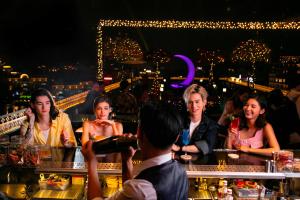 a group of people sitting at a bar at night at Aurora Premium - A Lifestyle Hotel in Hanoi