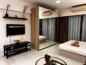 1 dormitorio con 1 cama, TV y espejo en Summer Suites KLCC By Homestay en Kuala Lumpur