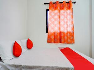 a bedroom with a bed with red pillows and a window at OYO Flagship RJ Hotel in Nagpur