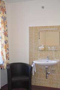 a bathroom with a sink and a black chair at Hotel Garni Schlossblick in Hohenschwangau