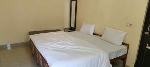 1 cama con sábanas blancas y almohadas en una habitación en Atithi Hotel, en Paliā Kalān