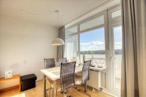 una sala da pranzo con tavolo, sedie e una grande finestra di Ferienpark - Haus A, App 0A0704 a Heiligenhafen