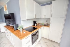 une cuisine avec des placards blancs et un comptoir en bois dans l'établissement Ferienpark - Haus A, App 0AEG06, à Heiligenhafen