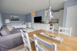 Il comprend une cuisine et un salon avec une table et un canapé. dans l'établissement Ferienpark - Haus A, App 0AEG06, à Heiligenhafen