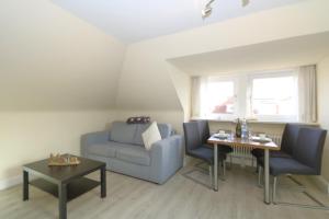 a living room with a blue couch and a table at Haus Sarah App 06 in Westerland +3 photos