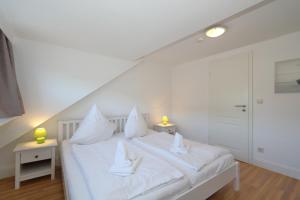 a bedroom with a white bed with white sheets and pillows at Haus Sarah App 06 in Westerland
