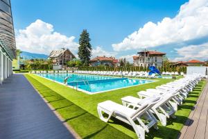 a row of white lounge chairs next to a swimming pool at Complex Europe in Dolna Banya