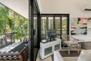 a living room with a television on a balcony at Julians Apartments in Byron Bay