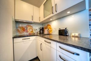 eine Küche mit weißen Schränken und Granitarbeitsflächen in der Unterkunft Ferienpark - Haus B, App 0B0408 in Heiligenhafen