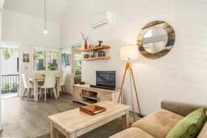 a living room with a couch and a tv and a table at Julians Apartments in Byron Bay