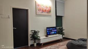 a living room with a tv on a cabinet with two plants at Tamu d'Bertam Homestay in Kepala Batas