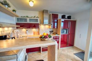 una cocina con armarios rojos y un bol de fruta en una barra en Ferienpark - Haus B, App 0B0606, en Heiligenhafen