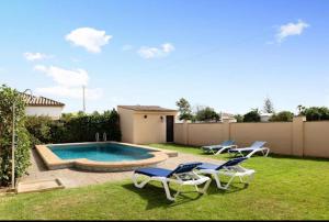 een tuin met 2 stoelen en een zwembad bij Villas Pérez Zara 1, 2 y 3 in Conil de la Frontera