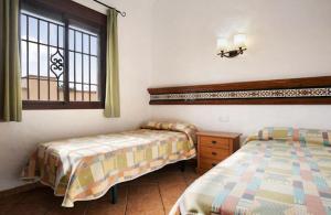een slaapkamer met 2 bedden en een raam bij Villas Pérez Zara 1, 2 y 3 in Conil de la Frontera
