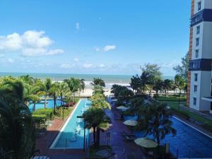 a view of the pool and beach from the balcony of a resort at Timurbay seafront residence in Kuantan