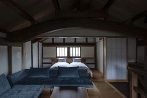1 dormitorio con 1 cama y 1 sofá en 滔々 日本郷土玩具館 蔵の宿 toutou, Gangukan Kura no Yado, en Kurashiki