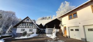ein weißes und schwarzes Haus mit Schnee auf dem Boden in der Unterkunft Schwarzwaldglück in Oberkirch