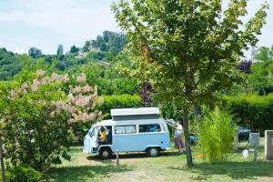 une camionnette bleue et blanche garée à côté d'un arbre dans l'établissement Camping Forcalquier les Routes de Provence, à Forcalquier