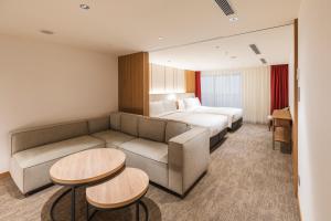 una camera d'albergo con divano, letto e tavoli di Sotetsu Grand Fresa Taipei Ximen a Taipei