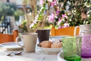 una mesa con platos y tazas y galletas. en Residence il Melograno, en San Teodoro