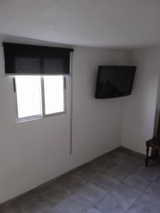 Habitación blanca con TV y ventana en Casa lucas, en Almáciga