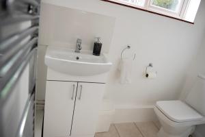 uma casa de banho branca com um lavatório e um WC em Tillyard Retreat, Ground Floor Apartment Cambridge em Cherry Hinton