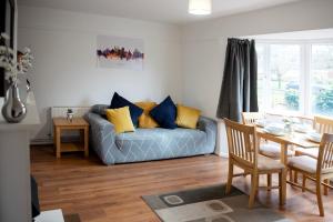 a living room with a blue couch and a table at Tillyard Retreat, Ground Floor Apartment Cambridge in Cherry Hinton