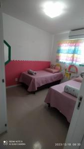 a bedroom with two beds and a pink headboard at Apartamento aconchegante em Itajaí in Itajaí