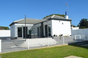 ein weißes Haus mit einem Zaun davor in der Unterkunft EL ENCANTO II PISCINA PRIVADA WIFI BARBACOA PARKING AIRE Ac in Chiclana de la Frontera