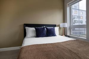 a bedroom with a bed with blue pillows and a window at Kendall Square studio w gym wd rooftop BOS-918 in Boston
