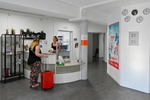 une femme avec une valise rouge debout à un comptoir dans l'établissement AUBERGE DE JEUNESSE D'ORLEANS, à Orléans