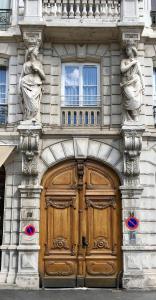 a building with a wooden door with two statues on it at Nid douillet avec vue in Lyon