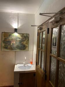 a bathroom with a sink and a painting on the wall at happy trust happy inn in Nuwara Eliya