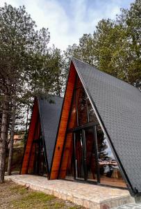 uma casa revestida a madeira com um telhado preto em Vilat Alpine Golden Gjinar em Elbasani